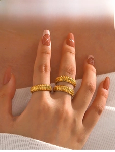 Detail of three stacked golden textured rings with striped patterns on a hand