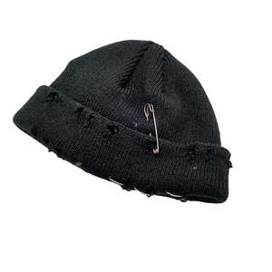 Détail du bonnet en maille noire vieillie avec épingles de sûreté et anneaux métalliques