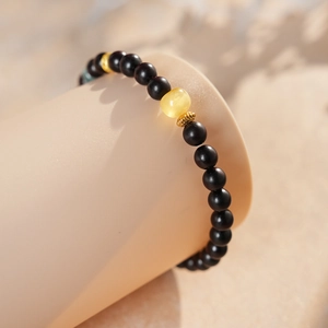Macro shot of sandalwood bracelet featuring amber bead and retro gold accents