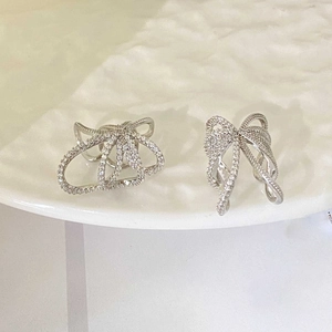 Close-up of silver bow ear clips with sparkling crystals on white ceramic tray
