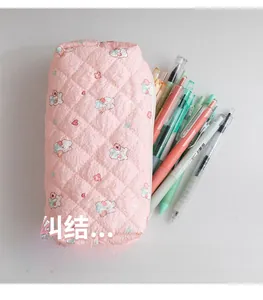 Close-up of pink quilted pencil case with rabbit floral print and multiple pens inside