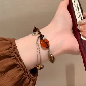 Close-up of a woven ethnic bracelet with orange carnelian bead on a model's wrist