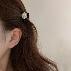Close-up of a mini black camellia hair claw clip worn on hair with white flower detail