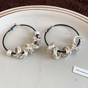 Macro view of hoop earrings with silver twisted rings and pearls on ceramic plate