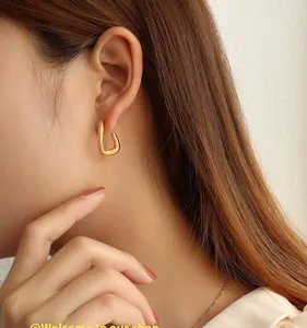 Close-up of minimalist C-shaped 18K gold-plated titanium earrings on a model