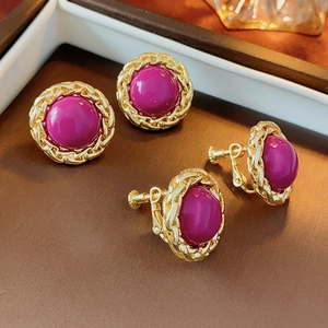 Macro detail of magenta cabochon earrings with vintage golden twisted chain border