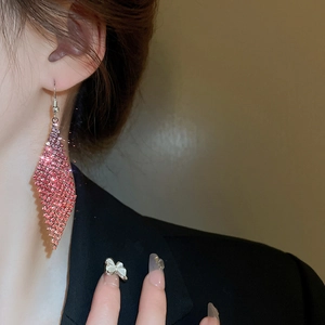 Gros plan de boucles d'oreilles losanges à strass roses portées par un mannequin