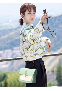 Detail of mint green crossbody bag with gold crown charm and chain strap