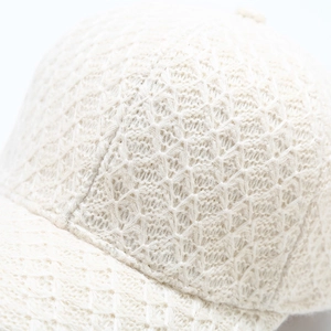 Detailed macro view of the intricate white lace knitted texture on this warm baseball cap