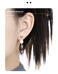 Close-up of asymmetrical long pearl earrings with rose gold finish worn on ear