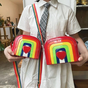 Detail of glossy rainbow striped crossbody bags featuring a red heart and fabric strap