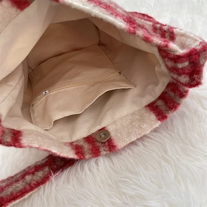Detail view of red checkered plush bucket bag featuring zip pocket and magnetic closure