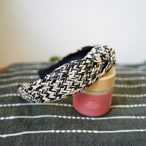 Close-up of woven raffia headband with black and white knot on striped fabric