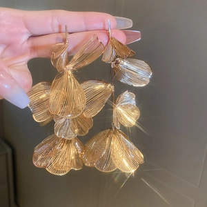 Detailed macro view of large layered gold wire mesh flower drop earrings for gala events