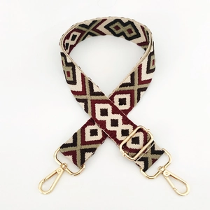 Close-up of geometric jacquard bag strap with golden metal buckles on white background