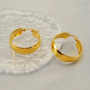 Polished 18k gold plated stainless steel chunky hoop earrings on textured glass surface
