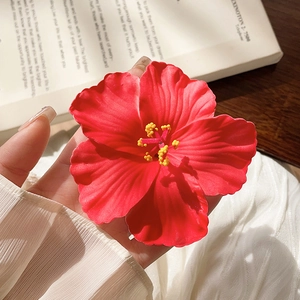Macro shot of a red frangipani hair clip with realistic fabric texture and yellow stamens