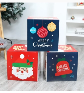 Three festive Christmas gift boxes with Santa and bell prints on a wooden floor