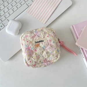 Detail of quilted sanitary pad storage pouch with floral patterns and pink cord zipper
