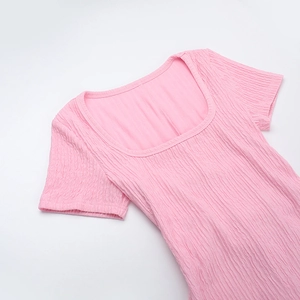Détail d'une robe rose à col carré avec un tissu texturé plissé et des manches courtes