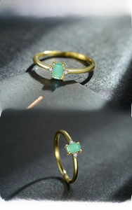Detail of a 925 silver gold-plated ring with rectangular green gem and side diamonds