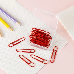 Top view of vibrant red paper clips organized in a clear plastic storage box on a pink desk