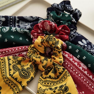 Four paisley print hair scrunchies with long streamers in yellow, red, green and navy