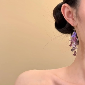 Boucles d'oreilles pendantes papillon violettes élégantes portées par un mannequin