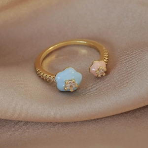 Detail of gold open ring with colorful enamel flowers and shimmering zircon pavé accents