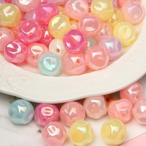 Macro shot of iridescent round acrylic beads spilling from a white decorative tray for DIY