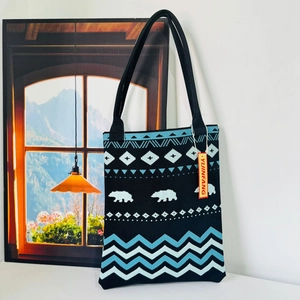 Detailed view of black knitted tote bag featuring blue white polar bear and wave patterns