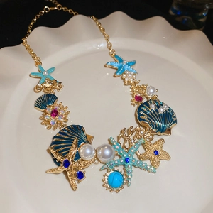 Detailed macro view of gold starfish necklace with blue enamel and pearls on a white plate