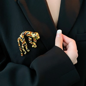 Detailed view of an enamel tiger brooch with green gemstone eyes on a black blazer