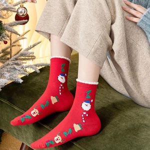 Red Christmas crew socks with Santa Claus patterns and white faux fur trim on model