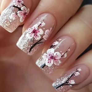 Close-up of long coffin press-on nails featuring pink sequin gradient and plum blossoms