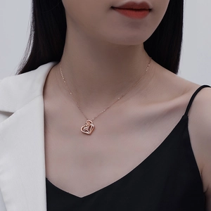 Close-up of rose gold heart pendant with rose detail worn by model on a fine chain