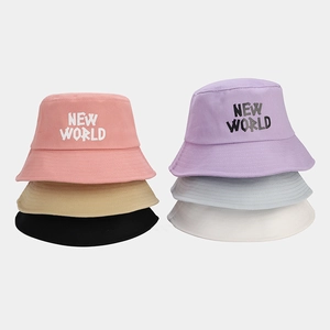 Detail of colorful cotton bucket hats with NEW WORLD lettering in pink, blue, and black