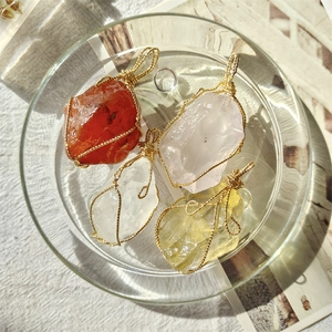 Detailed shot of four handcrafted wire-wrapped natural crystal pendants on a glass tray