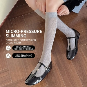 Grey calf-high ribbed compression socks for women paired with black Mary Jane shoes