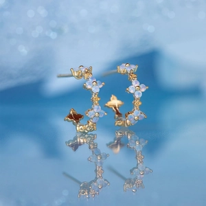 Macro shot of 18K gold plated flower earrings with blue petals and mirror reflection
