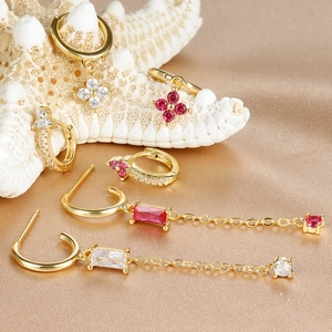 Detail of gold floral earrings and rose zircon tassel chains on golden silk fabric