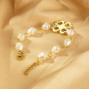 Detail of baroque pearl bracelet with gold clover pendant on luxury satin fabric