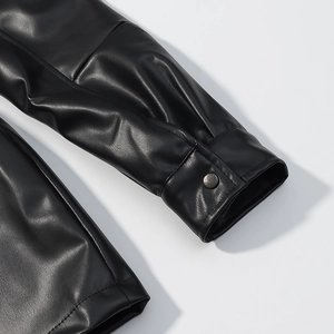Detail of black leather sleeve with metal fastener and premium stitched texture