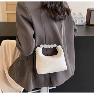 Detail of white lychee leather dumpling bag with transparent pearl bead handle strap