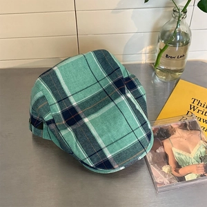 Detail of green plaid flat cap with mint and navy tartan pattern in retro setting