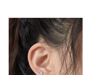 Close-up of small blue enamel flower earrings with gold center on model ear