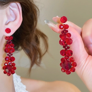 Detailed view of long red faceted crystal bead tassel earrings with floral pendant design