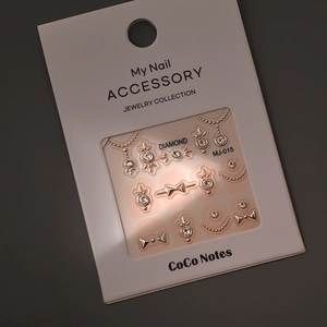 Detail of 3D gold nail charms with rhinestones and bows on display card