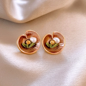 Detail of vintage gold flower earring with pink enamel and a central pearl on silk