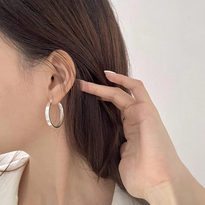 Close-up of minimalist large S925 sterling silver hoop earring worn by a model
